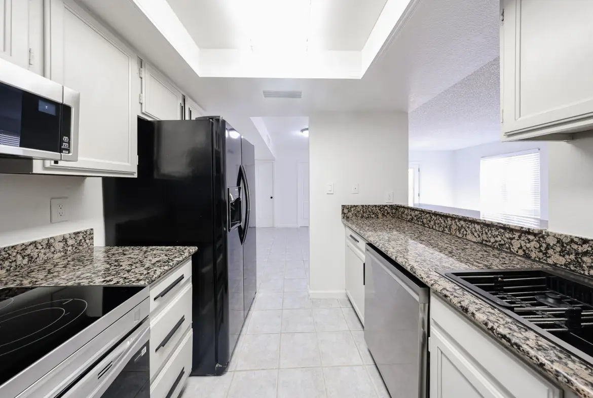 Updated kitchen with white cabinetry and dark appliances
