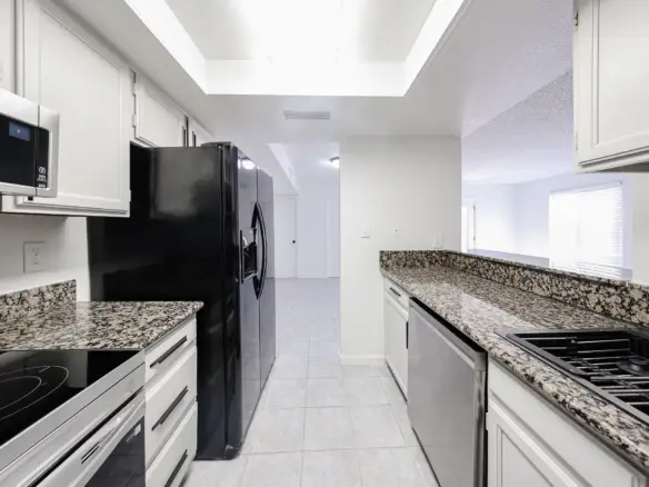 Updated kitchen with white cabinetry and dark appliances