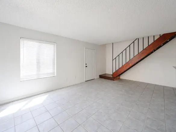 Living room view showing the staircase to the second floor